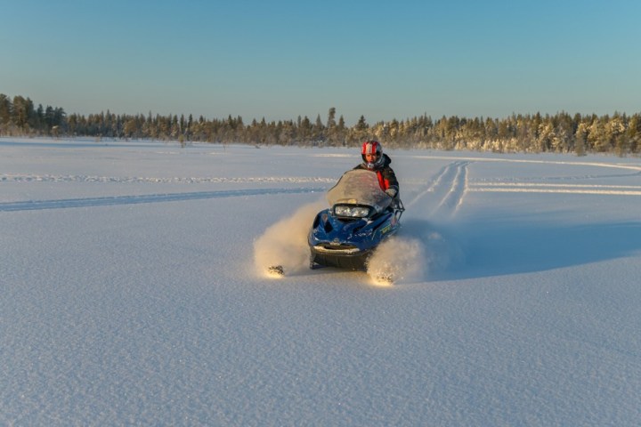 a man riding a motorcycle down a snow covered road